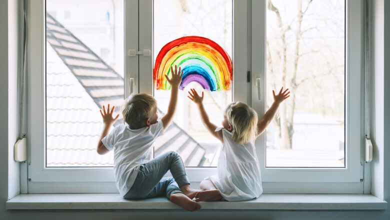 Childer drawing a rainbow on a window